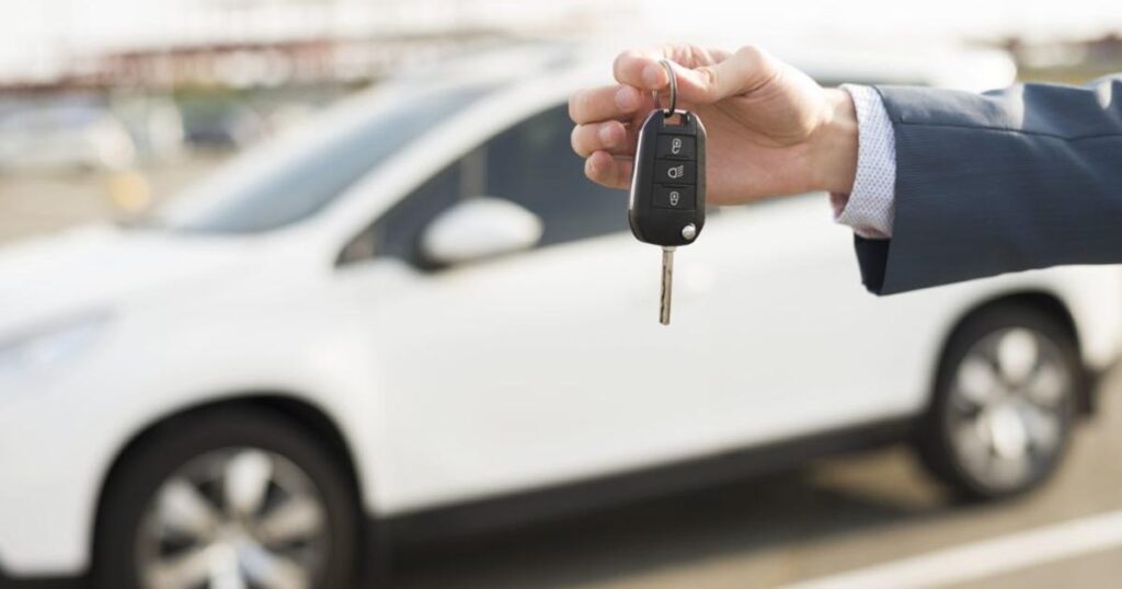 homem com chave na mão do carro semi novo adquitrido com consórcio